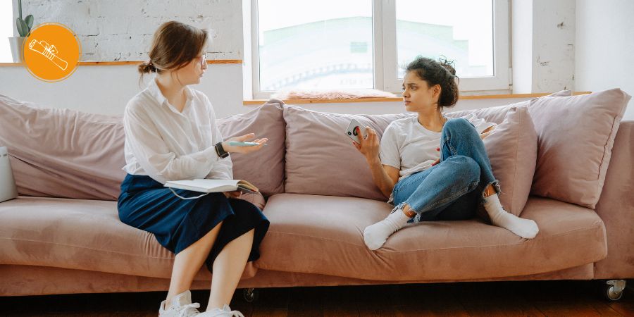 Frau sitzt auf Sofa und spricht mit Therapeutin über Trauma